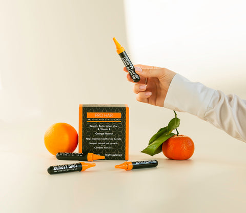 Pro Hair Liquid Vitamins box held by a woman's hand, showcasing an open shot. The box features vibrant branding and the words 'Pro Hair Liquid Vitamins' in bold. The woman's hand effortlessly holds the open shot, revealing the convenient flip-top lid for easy consumption. The image portrays the seamless integration of hair vitamins into your daily routine, adding a touch of haircare luxury to your life.