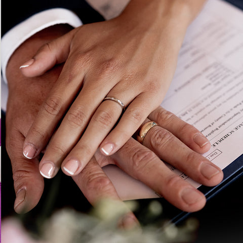 Brides hand on top of grooms hand showing off both of their wedding rings