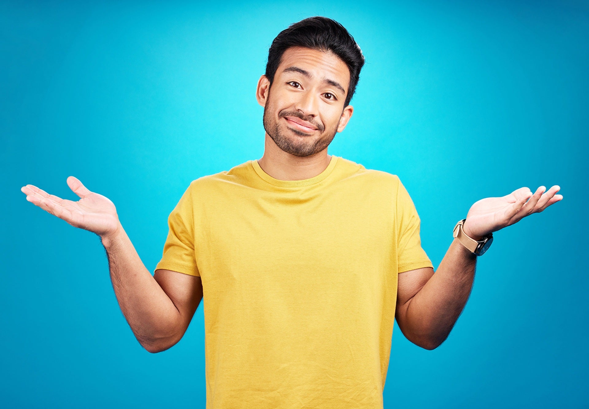 Question and portrait of man shoulder shrugging and raise arms isolated in a blue studio background.