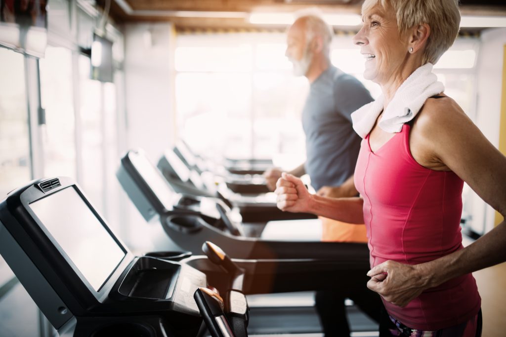 woman and man on treadmills at a gym