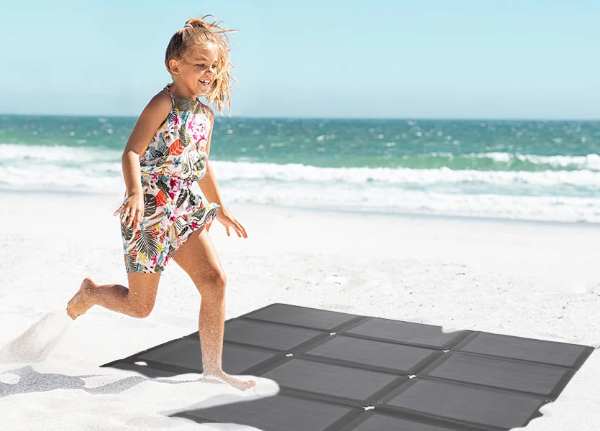 Ein Mädchen, das am Strand auf das faltbare Solarmodul von BougeRV tritt
