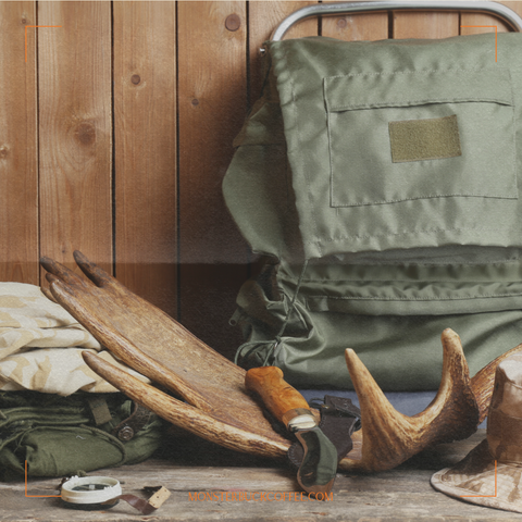 A moose antler sitting next to a sharp knife, a backpack and a compass. Things you may need for hunting.