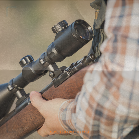 A man holding a hunting rifle with a scope on it.