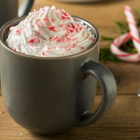 Peppermint Mocha in a dark grey mug with candy cane sprinkles on top.