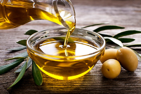 In a miniature bowl, the liquid gold of extra virgin olive oil gleams, accompanied by plump olives and delicate olive leaves, promising a taste of Mediterranean indulgence.