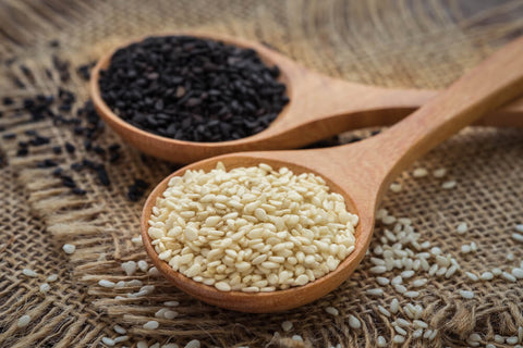 FUN Sesames | Monochrome image showcasing sesame seeds elegantly arranged in a wooden spoon, highlighting the contrast and texture in black and white.