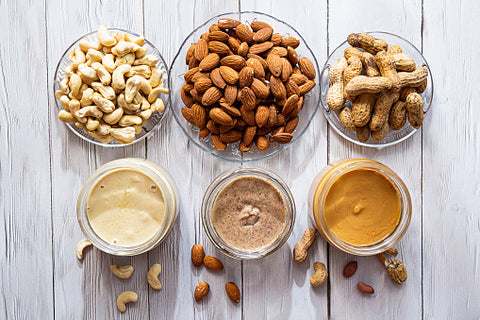 An enticing array awaits: three bowls brimming with cashew nuts, almond nuts, and peanuts, each accompanied by a container filled with its creamy counterpart—cashew butter, almond butter, and peanut butter. A delightful spread of nutty goodness, ready to elevate your culinary creations.