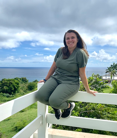 Smiling vet student sits on a fence to pose for photo