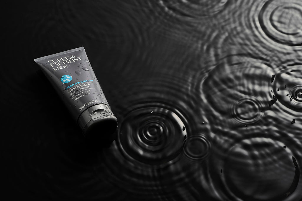 moisturiser tube on black water with droplets around it skincare for men