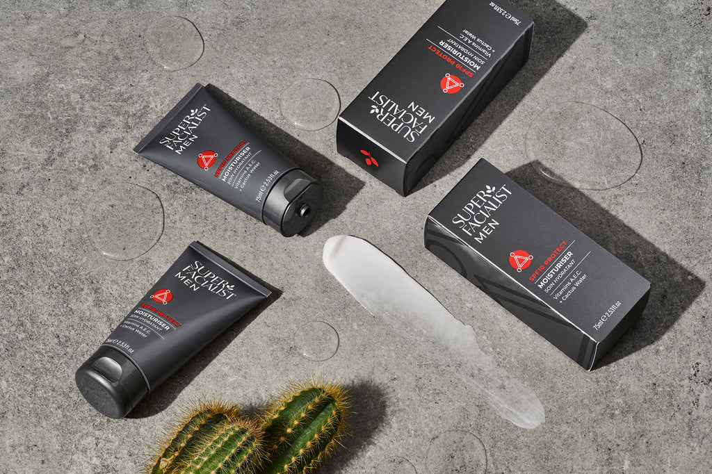 spf10 moisturiser tubes and cartons lying on stone with swatches of ingredients around it skincare for men