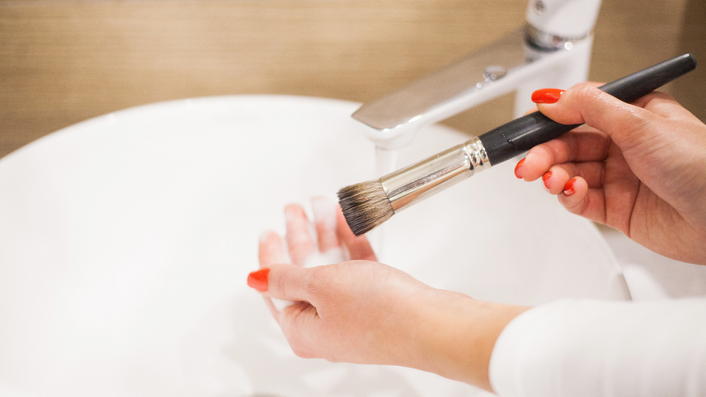 Woman washing make up brushes in a sink