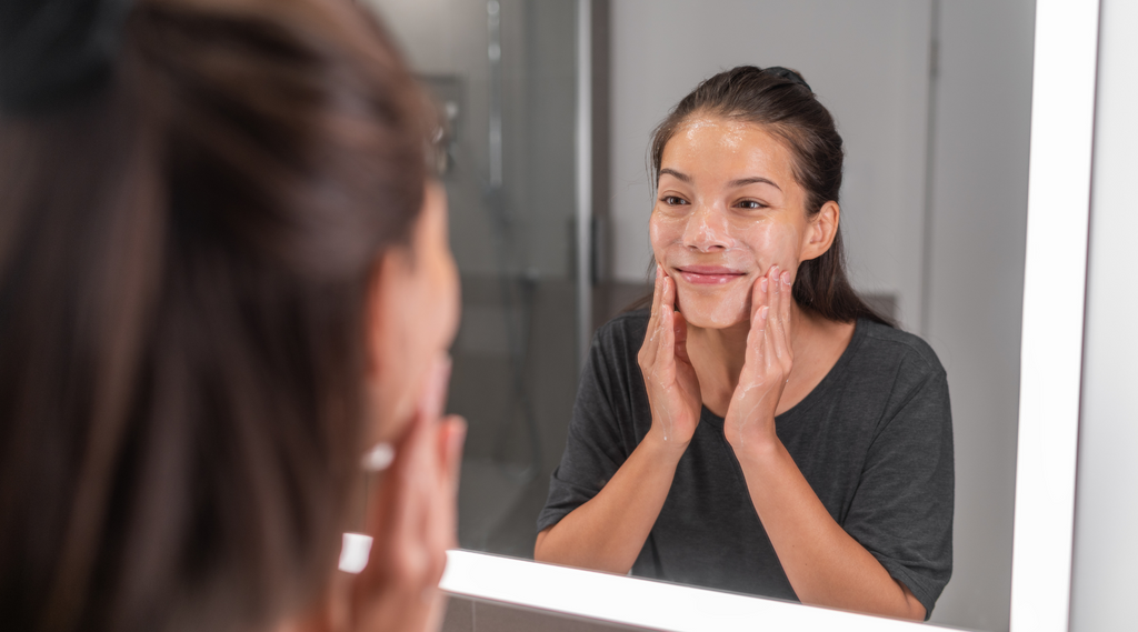 woman cleansing her face with gel cleanser in bathroom