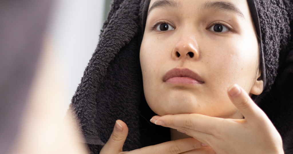 woman with hair towel massaging her face