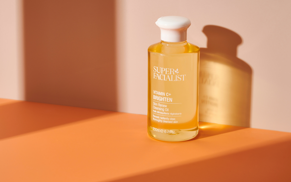 vitamin c cleansing oil against a shadow on an orange background