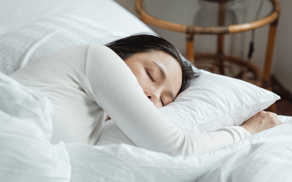 woman with black hair sleeping on white bedding as skincare best practice