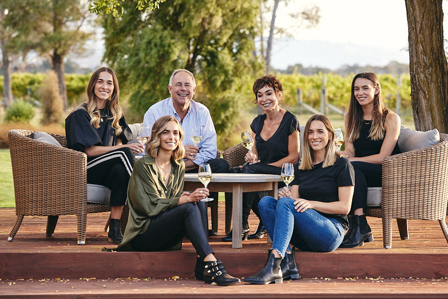 Marris family drinking wine on a deck with vineyards in the background