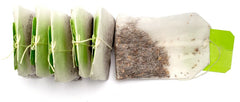 Line of tea bags with green tags and one lying on its side