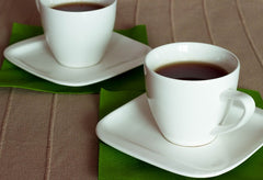 Picture of two white cups and saucers with tea in them