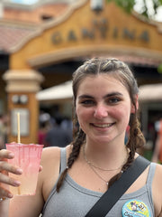 A woman with brown French braids celebrating her 21st birthday with a diablo margarita in front of the Mexico cantina at Disney's Epcot Park