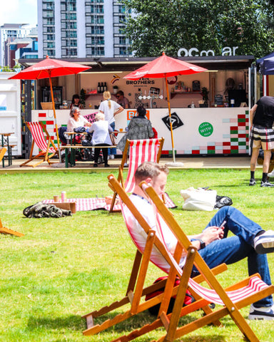 A photo of people sat in deck chairs outside box on the dox.