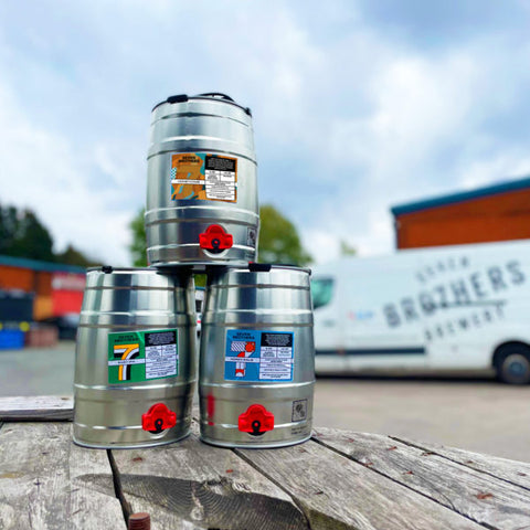 3 mini kegs on an outdoor wooden table.