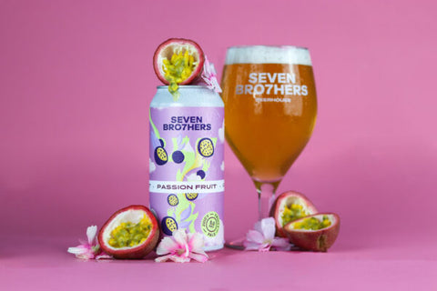 A can of passion fruit pale with a glass poured and passion fruits around it.