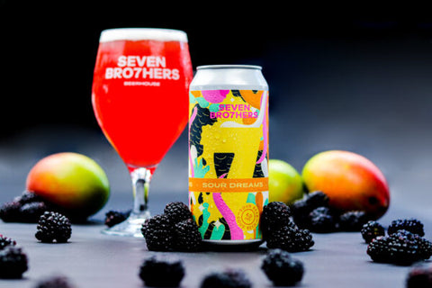 A can of Sour Dreams with a glass poured next to it surrounded by fruit.