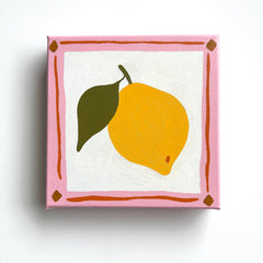 canvas oil painting of a bright yellow lemon with olive green leaf and a pink and orange border