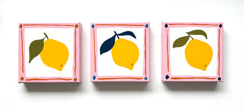 three canvas oil paintings of bright yellow lemons with olive green and navy blue leaves and a pink and orange border