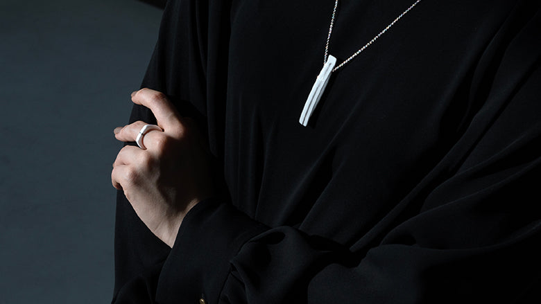BLANCERA Platinum Lineのネックレスとリングを着用した黒いニットの女性