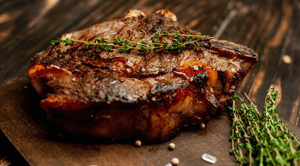 grilled-beef-steak-cutting-board-with-spices-lemon-wood-background