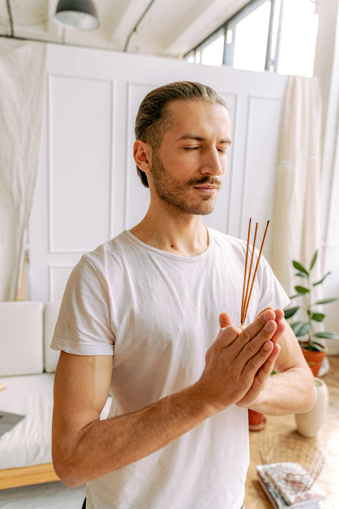 peaceful man holding incense sticks