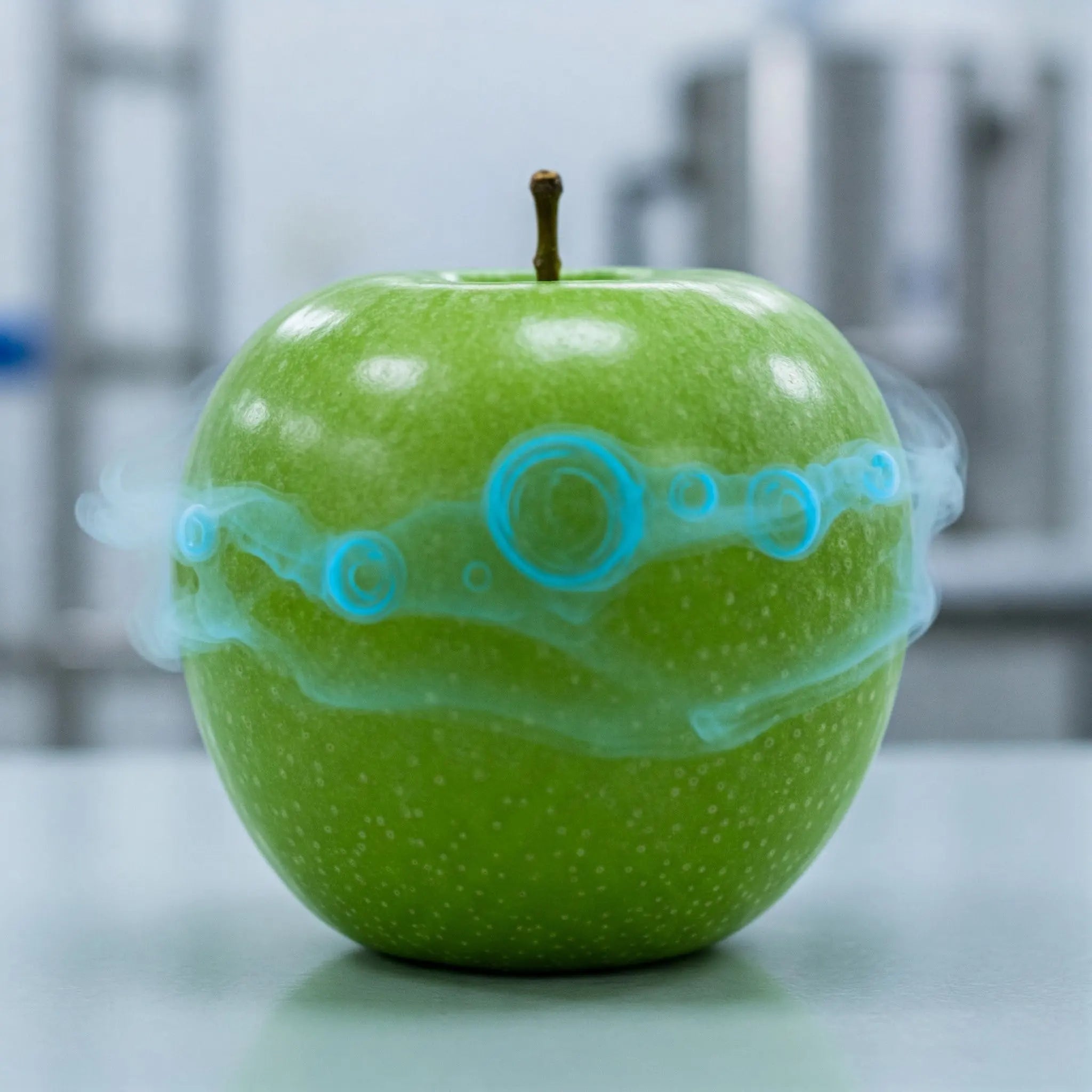 A green apple emitting blue smoke, creating a surreal and intriguing visual effect.
