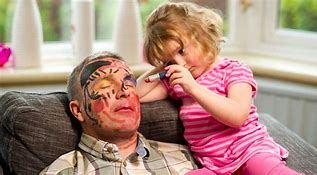 Little girl drawing on sleeping man's face.