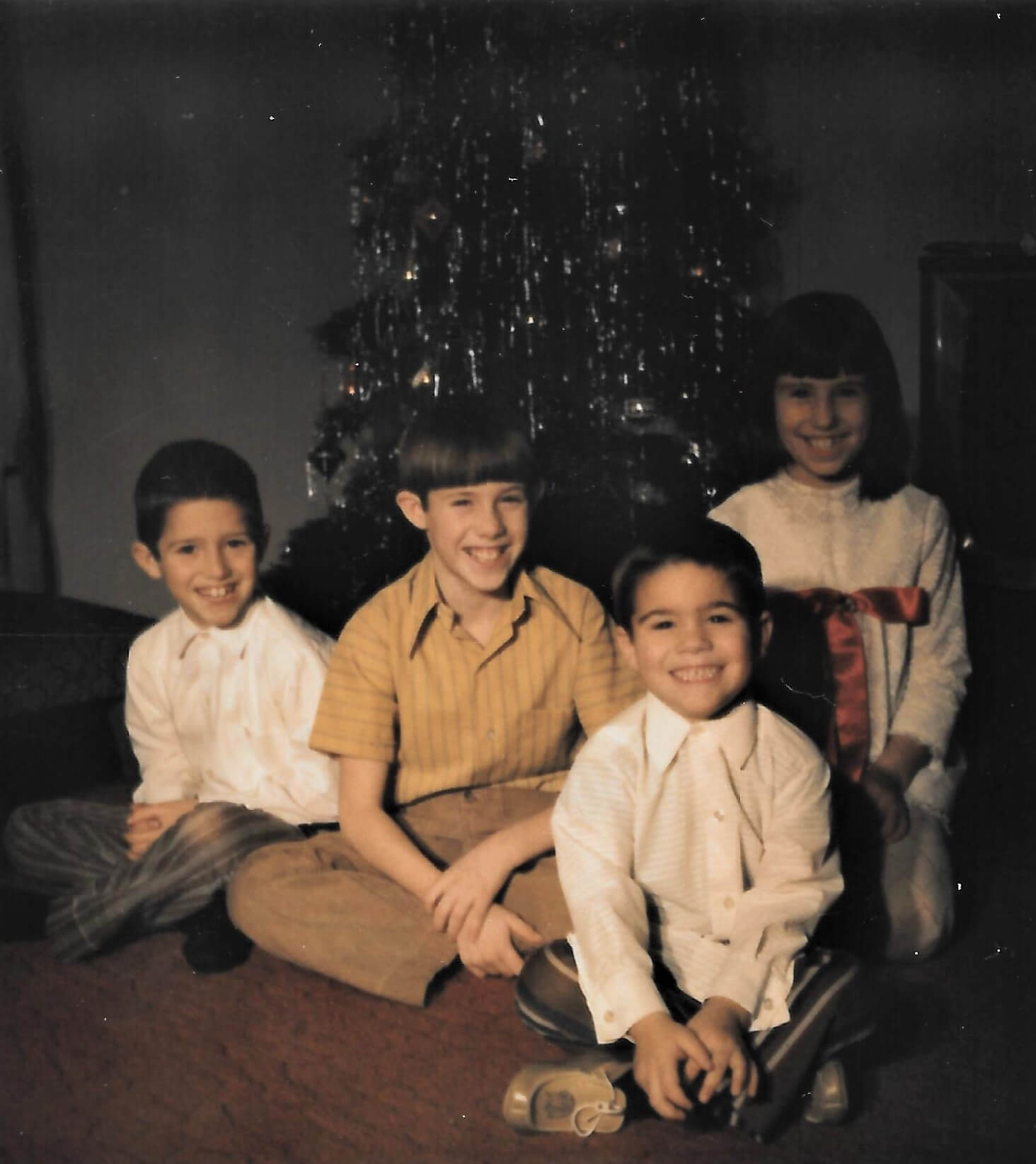 Mike and his siblings in front of a Christmas tree