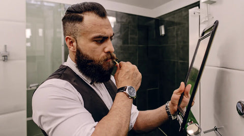 man die zijn baard verzorgt in de badkamer