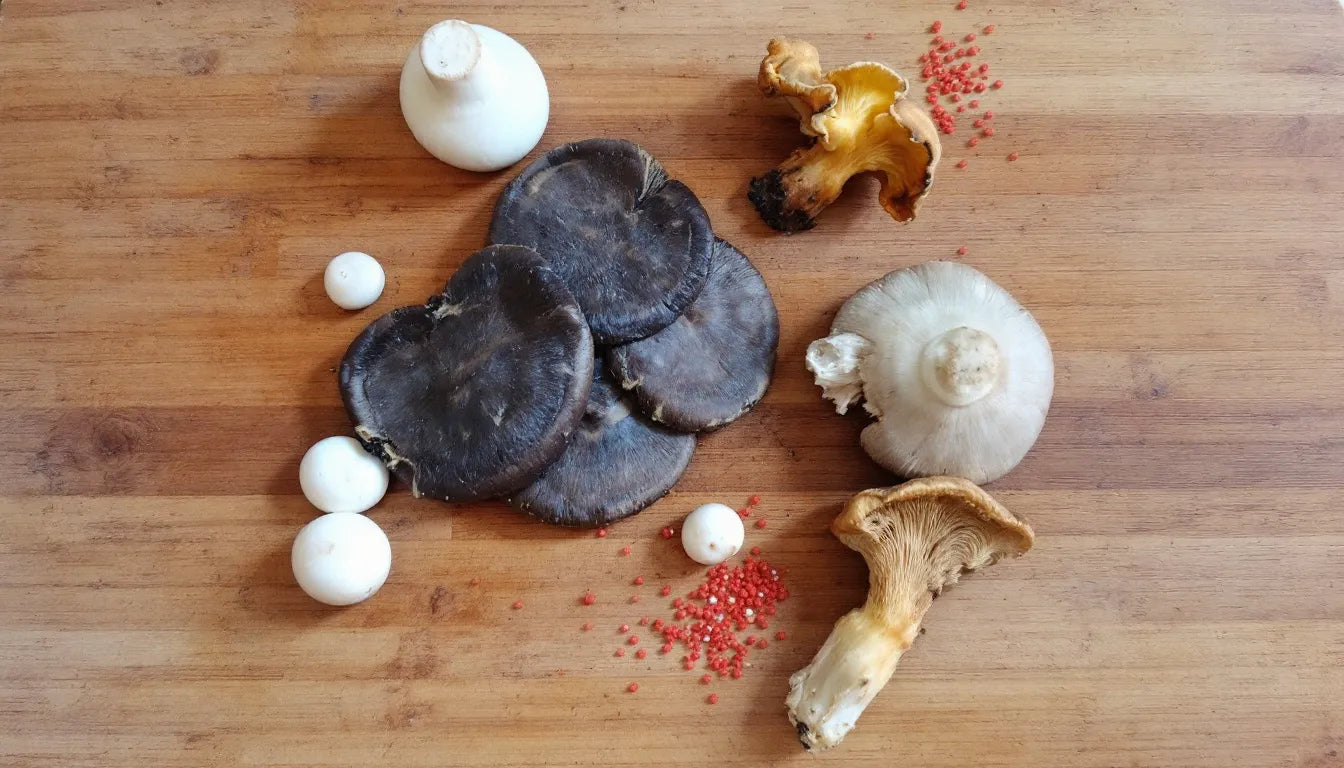 Assorted fresh mushrooms including shiitake and cremini on wood