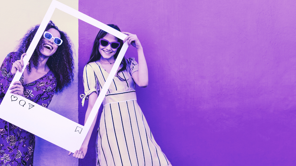 2 women smiling with a social media content photo booth prop.