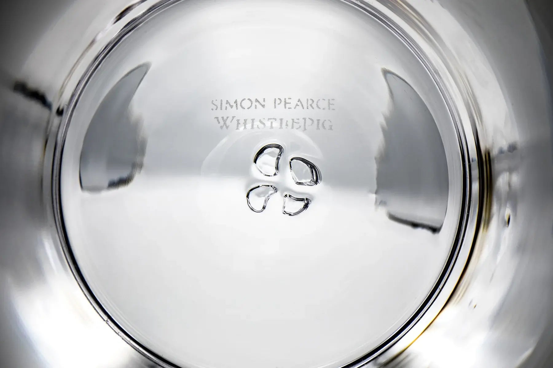 Engraved text inside a clear, reflective glass bowl: 'Simon Pearce WhistlePig.'