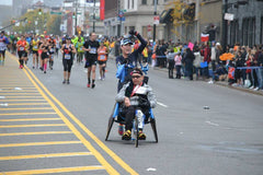 The Kyle Pease Foundation volunteer pushing an assisted athlete during a marathon