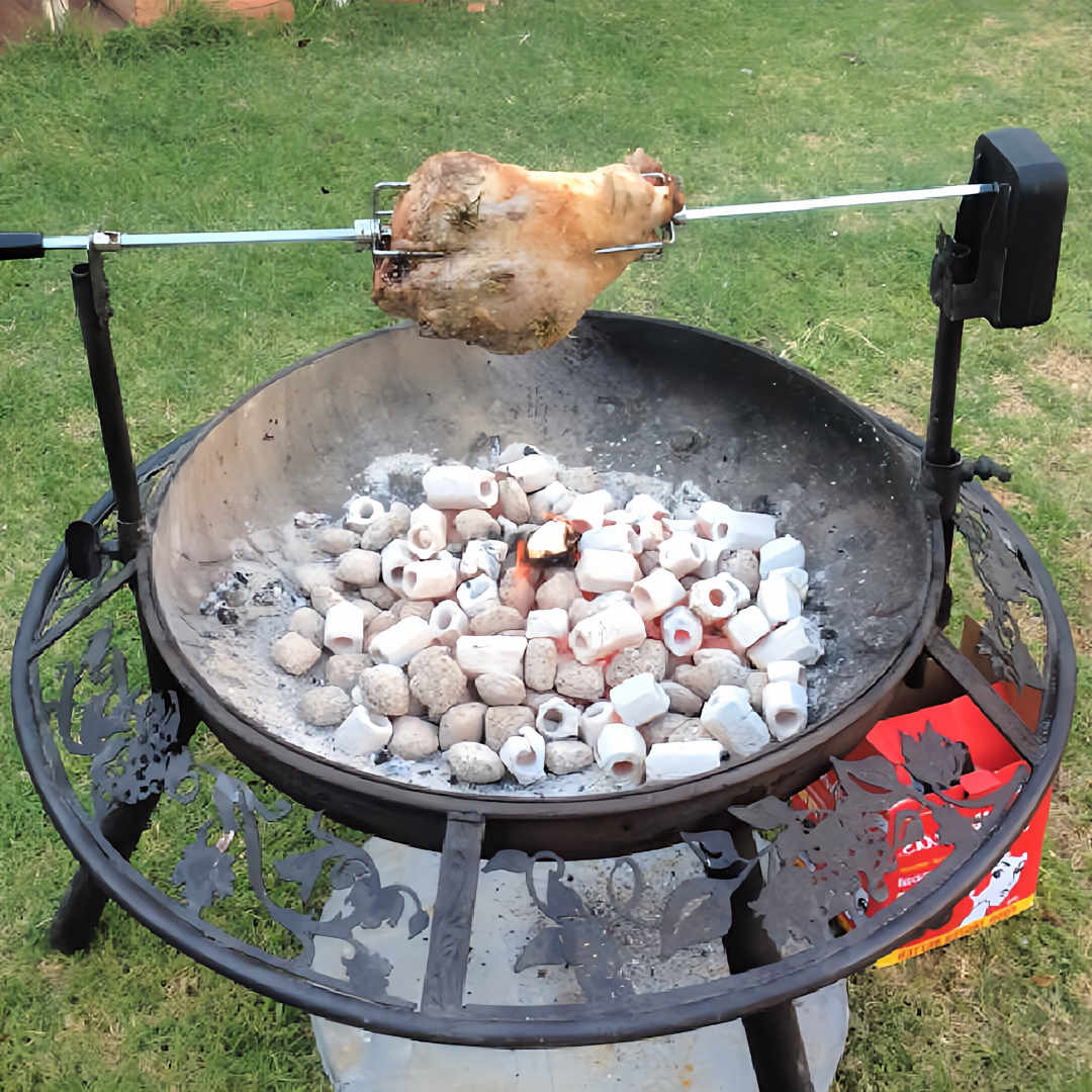 BBQ Fire Pit and Grill with a two pole spit attached cooking a roast lamb over hot coals