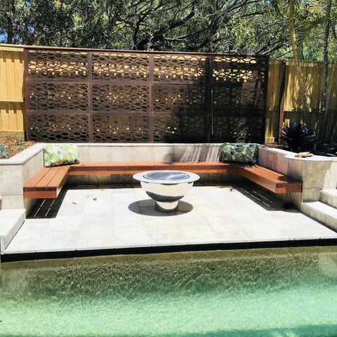 Stainless Steel fire pit next to a pool water feature showing a beautiful outdoor fire pit setting