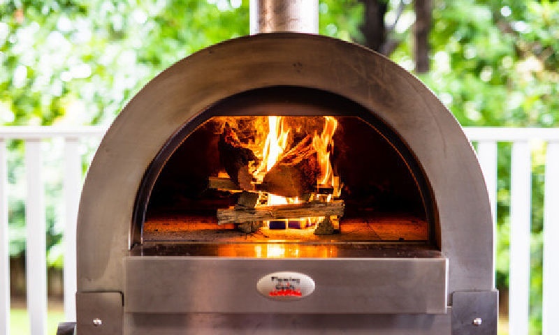 a front view of the wood fired pizza oven with a fire burning inside