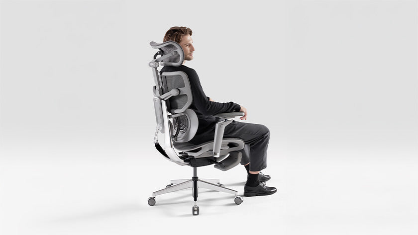 Man seated in a high-back X1 ergonomic chair with adjustable headrest.
