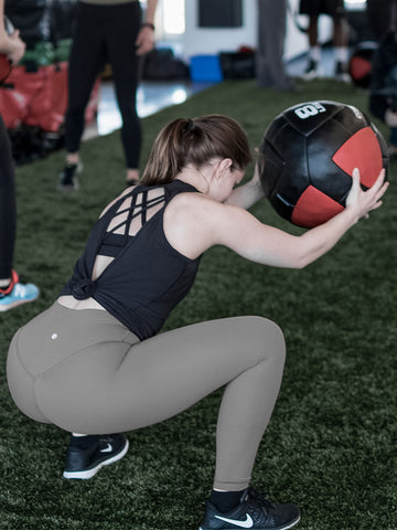 Girl squatting with Wall Ball