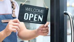 Staff hanging "We're Open" sign.