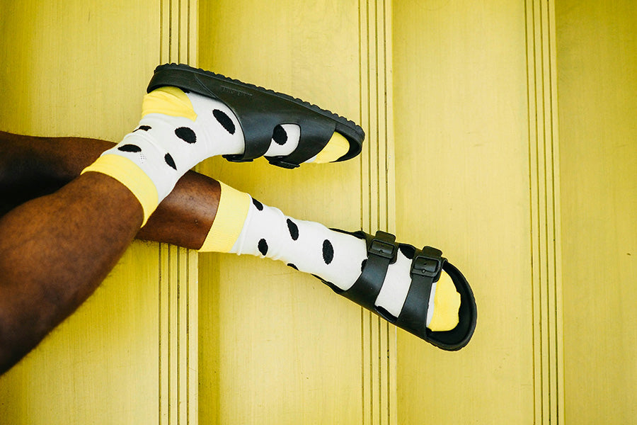 Polkadot socks with yellow trim in a pair of black slide sandals.