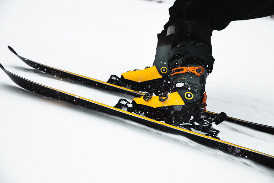 Yellow ski boots buckled into a pair of skis