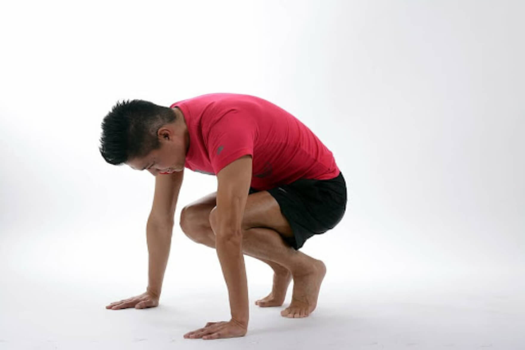 man performing a crouching stretch for the soles of his feet 