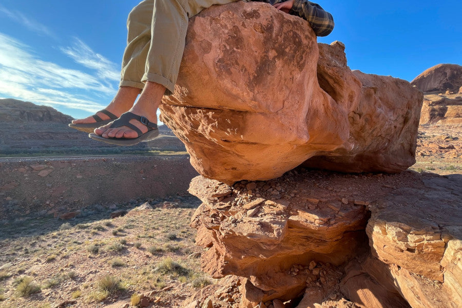 man lying on rocky terrain with Tread Labs hiking sandals